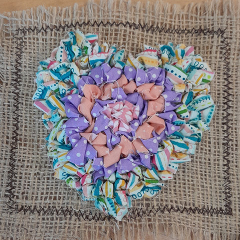 A colourful fabric broach in the shape of a heart.