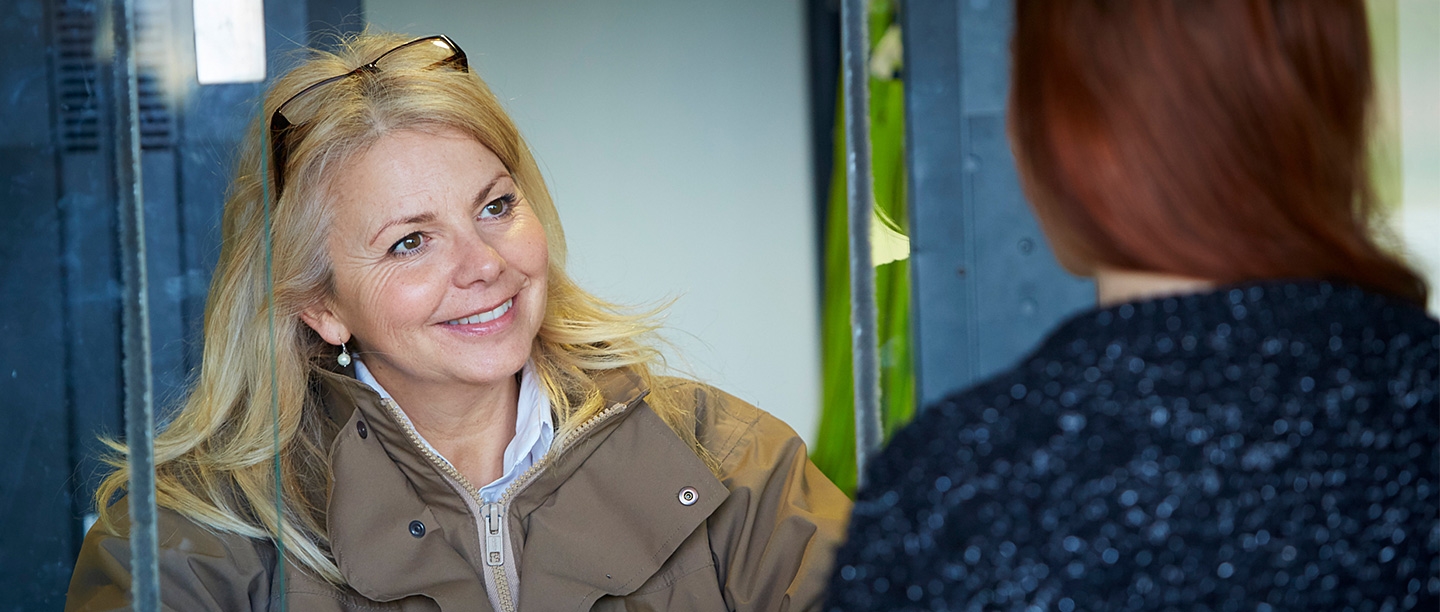 A woman with glasses on her head smiles at a visitor