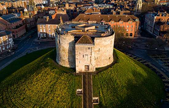 A squat tower (Clifford's Tower) sits on a large grass mound