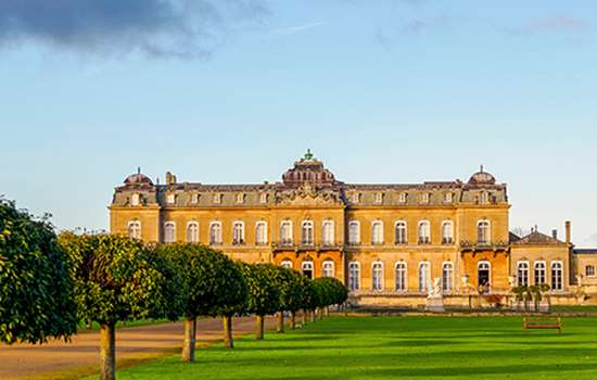 Looking across lawns to the large French-looking country house (Wrest Park) which looks amber in the evening sun