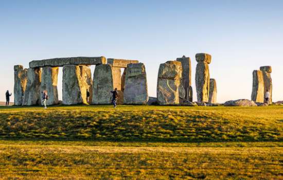 The large stone circle of Stonehenge seen across some grass